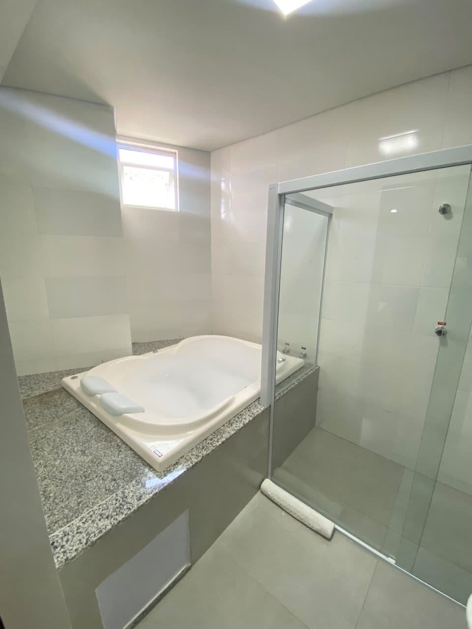 Un baño con ducha de vidrio, bañera y encimera de granito.