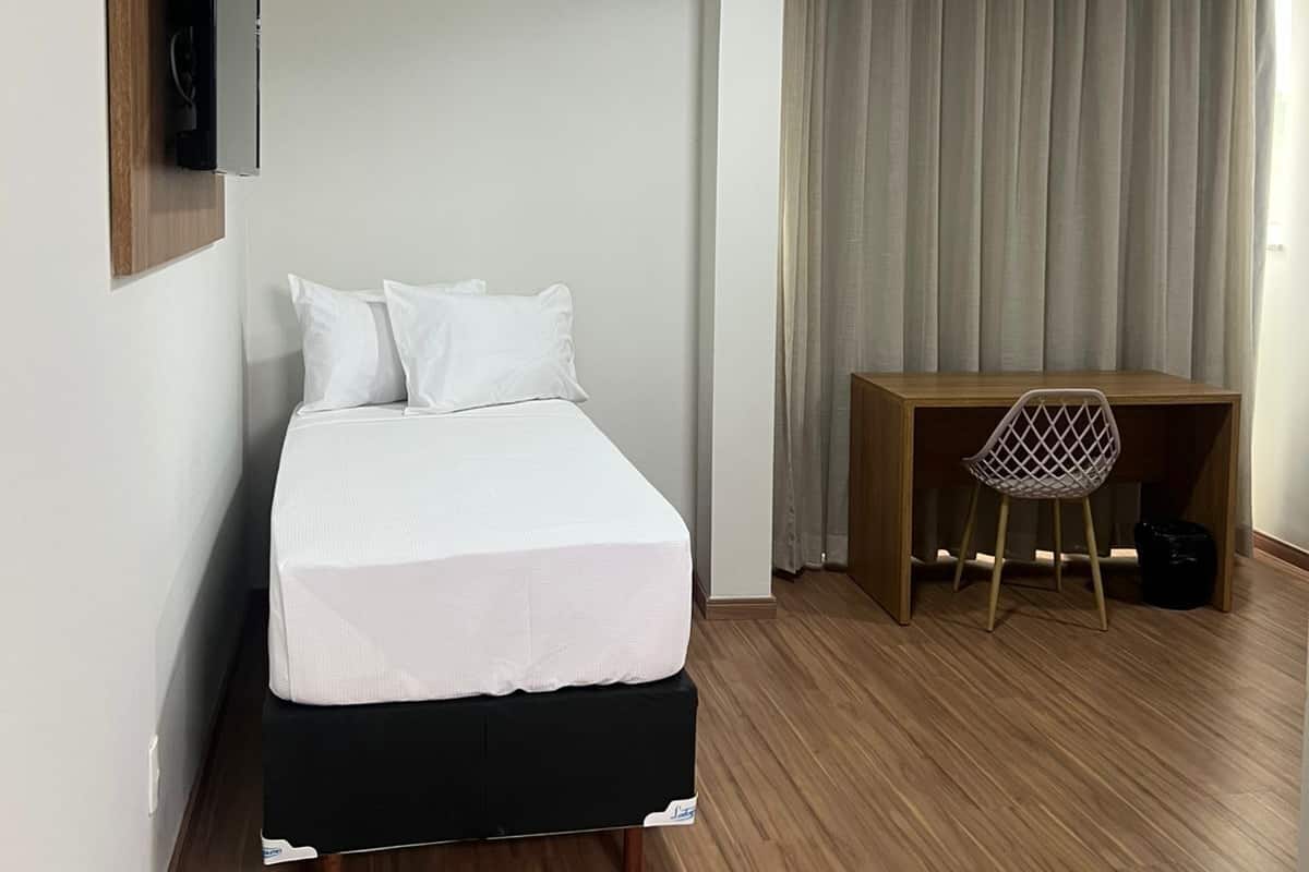 A bedroom with a bed, a desk, and a chair.