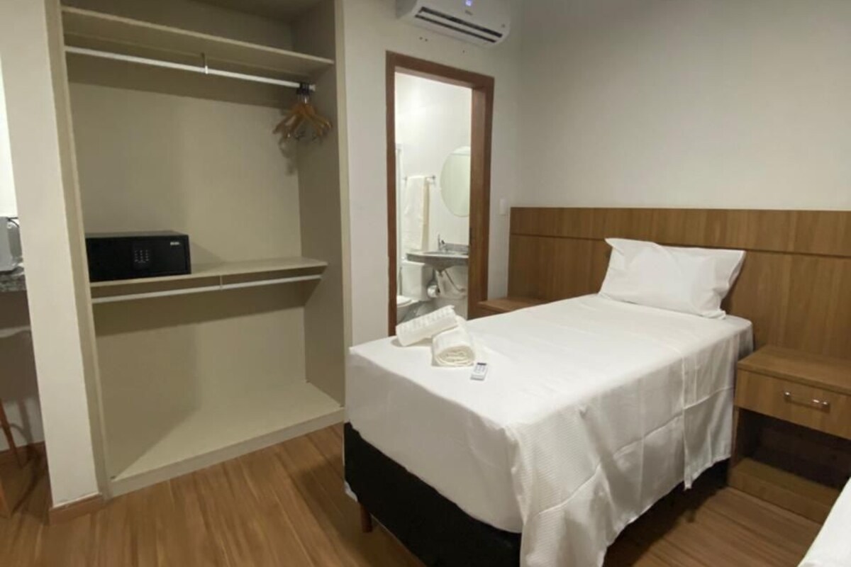 A bedroom with a bed, a wooden headboard, a wardrobe, and a small desk.