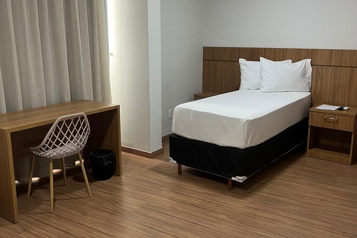 Une chambre d’hôtel avec un lit, un bureau, une chaise et une table de chevet.