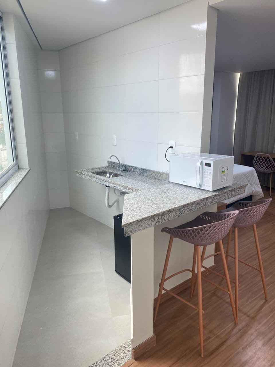 A kitchen with a granite countertop, a built-in sink, a microwave, and two wooden stools.