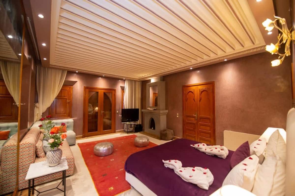 Una habitación de hotel con una cama grande, un sofá, un televisor y una chimenea.