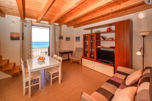 A living room with a wooden ceiling, a dining area with a table and chairs, a sofa, and a television. - Casa Tramonto a Cefal by Wonderful Italy (Cefalù)