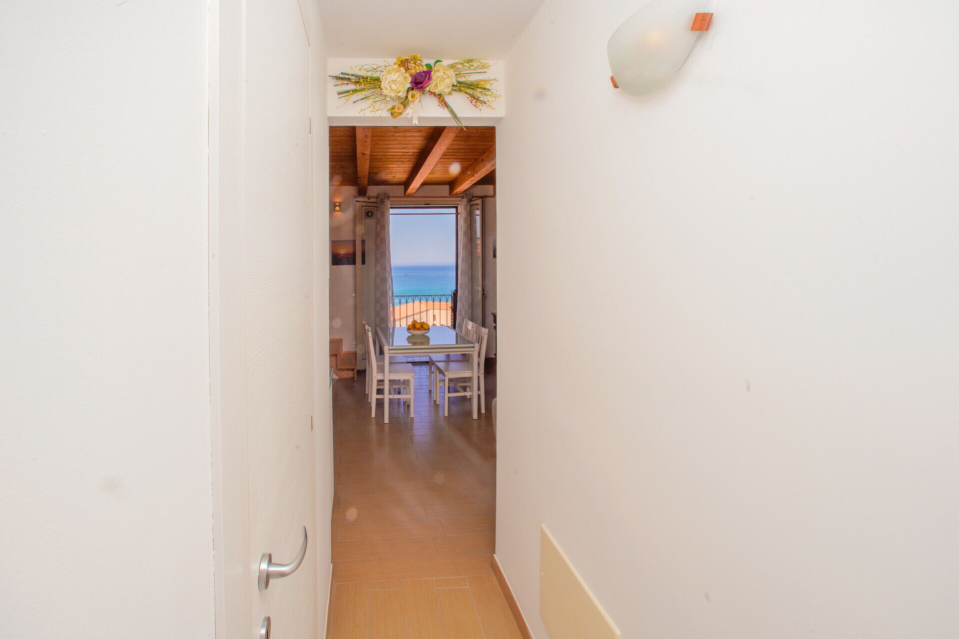 A narrow hallway leading to a dining area with a view of the sea.