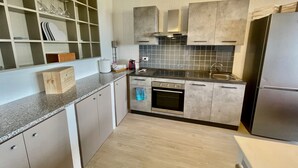 Una cocina moderna con horno empotrado, electrodomésticos de acero inoxidable y un salpicadero de azulejos.