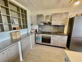 Una cocina moderna con horno empotrado, electrodomésticos de acero inoxidable y un salpicadero de azulejos.