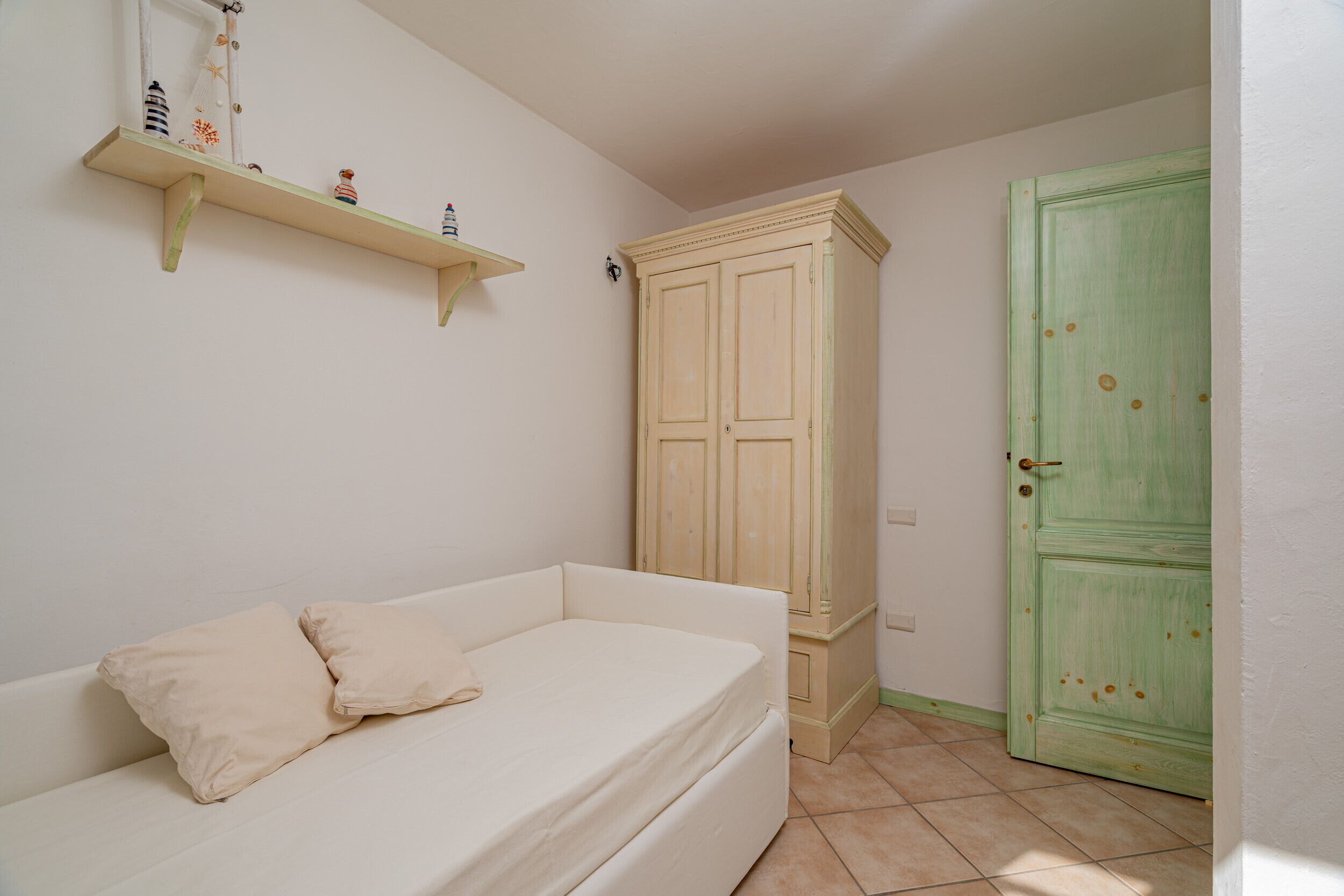 A bedroom with a bed, a wardrobe, and a green door.