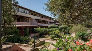 A multi-story building with a garden courtyard, featuring a staircase, various shrubs, and a clear sky. - Casa Graziana by Wonderful Italy (Olbia)