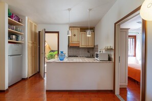 Eine kompakte Küche mit einer zentralen Kochinsel, Holzschränken und einem Kühlschrank.