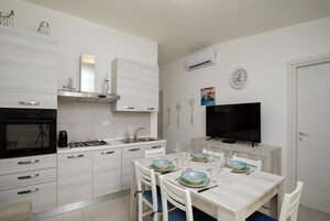 Una cocina moderna con armarios blancos, estufa a gas, horno empotrado y televisor de pantalla plana.