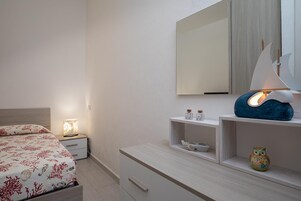 Un dormitorio con cama, mesita de noche, tocador y espejo.