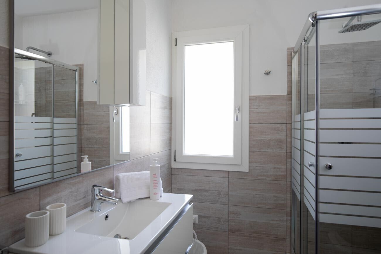 A modern bathroom with a large mirror, a sink, and a shower area.