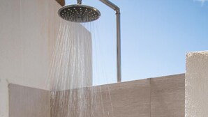 A shower area with a rain showerhead, a shelf with two bottles, and a flush toilet. - Casa Perla by Wonderful Italy (Olbia)