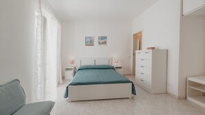Un dormitorio con cama, una silla, una mesita de noche, un aparador y un armario.