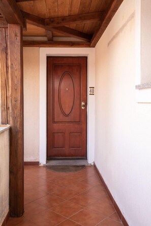 A hallway with a wooden door, white walls, and a tiled floor. - Casa Olbiamare by Wonderful Italy (Olbia)