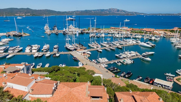 A marina with numerous boats docked, surrounded by buildings with red-tiled roofs. - Casa Natal a by Wonderful Italy (Olbia)
