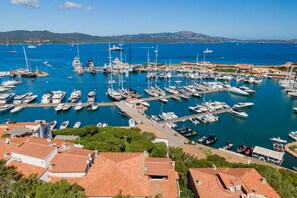 A marina with numerous boats docked, surrounded by buildings with red-tiled roofs. - Casa Natal a by Wonderful Italy (Olbia)