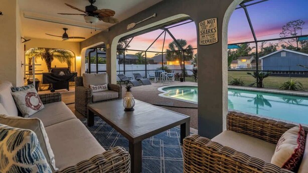 Une terrasse intérieure accueillante, avec des meubles en osier, une piscine et une vue imprenable sur le coucher de soleil.