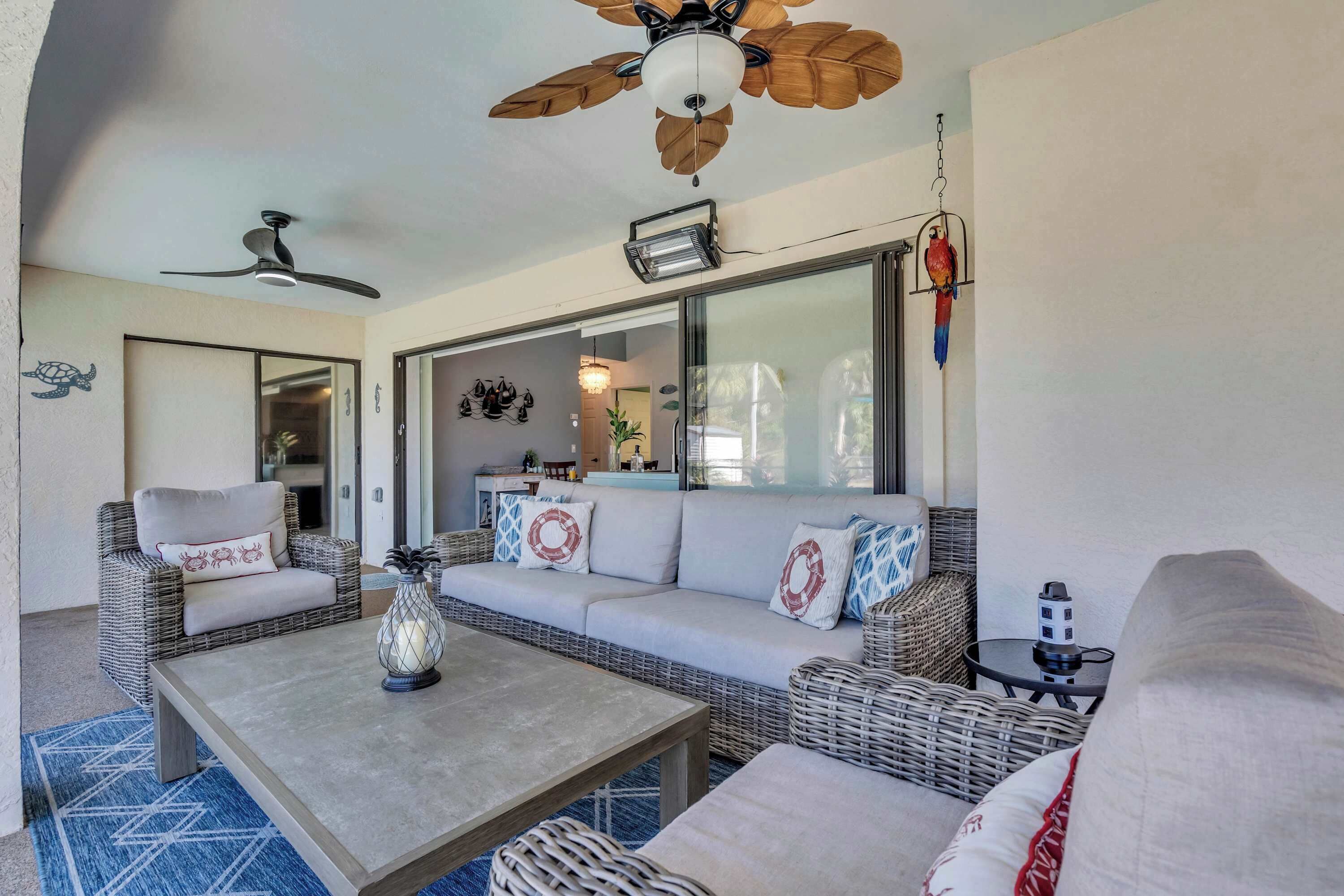 A cozy living area with wicker furniture, a ceiling fan, and a large window.