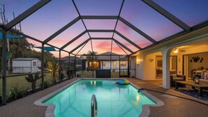 Une piscine intérieure dotée d’un toit en verre, entourée d’un patio aménagé avec des sièges et offrant une vue sur l’extérieur.