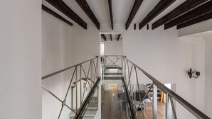 A modern interior with a staircase, glass railings, and a dining area with chairs and a table. - Appartamento Sammartino by Wonderful Italy (Palermo)