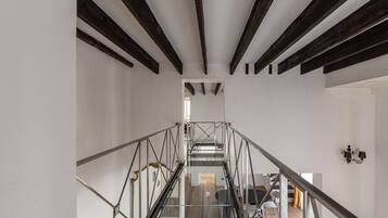 Un interior moderno con escalera, barandillas de vidrio y un comedor con sillas y mesa.