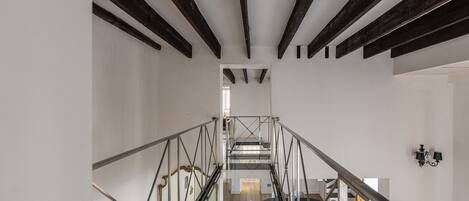 A modern interior with a staircase, glass railings, and a dining area with chairs and a table.