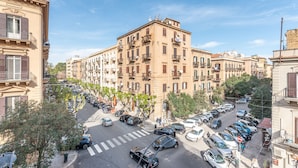 A multi-story building with balconies, parked cars, and a crosswalk. - Appartamento Sammartino by Wonderful Italy (Palermo)