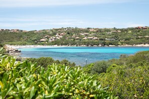 Paisagem costeira com casas numa encosta a espreitar para uma praia.