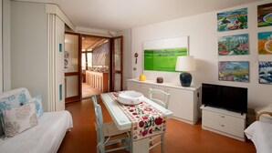 Een kamer met een bed, een eettafel met stoelen, een televisie en kunst aan de muur.