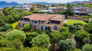 Eine Villa im mediterranen Stil mit Pool, umgeben von üppiger Vegetation und Bergen im Hintergrund.
