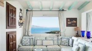 Una sala de estar con un sofá orientado hacia una ventana que ofrece vistas al mar.