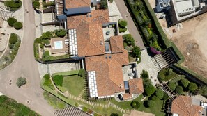 An aerial view of a building with a tiled roof, surrounded by landscaped gardens and a paved driveway. - Villa Maddalena a Cannigione by Wonderful Italy (Arzachena)
