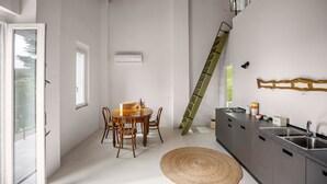 Una cocina moderna con comedor, una escalera y un ventanal grande.