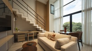 Ein modernes Wohnzimmer mit einer Couch, einem Couchtisch und einer Treppe, die in ein Obergeschoss führt.
