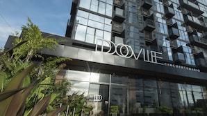 Un edificio moderno con fachada de vidrio y el nombre "DOVIL" visible en relieve.