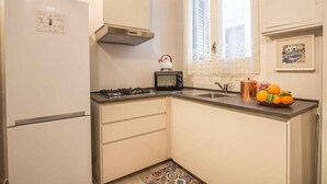A compact kitchen with a refrigerator, stove, toaster, sink, and a window with a view. - Suite Granatelli by Wonderful Italy (Palermo)