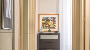 A hallway leading to a room with a framed artwork, a dark-colored dresser, and a red rug on the floor. - Suite Granatelli by Wonderful Italy (Palermo)