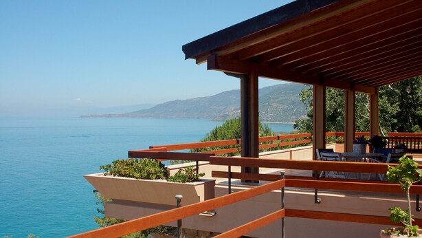 Une terrasse avec vue sur la mer, des rampes en bois et des sièges d’extérieur.