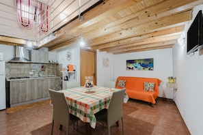 Una cocina con una mesa de comedor, sillas, un sofá y una televisión.