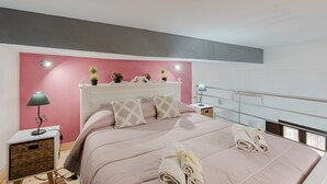 Ein Schlafzimmer mit Bett, Nachttischen, einer Lampe, einem an der Wand befestigten Regal mit Pflanzen und einem Fenster mit Blick.