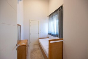 A small, single-bed room with a wooden headboard, a bedside table, a wardrobe, and a door. - VESTA - Gouna Residence  (El Gouna)