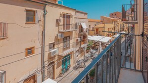 A narrow urban street with buildings featuring balconies and outdoor seating areas. - Casa Silvana a Cefal by Wonderful Italy (Cefalù)