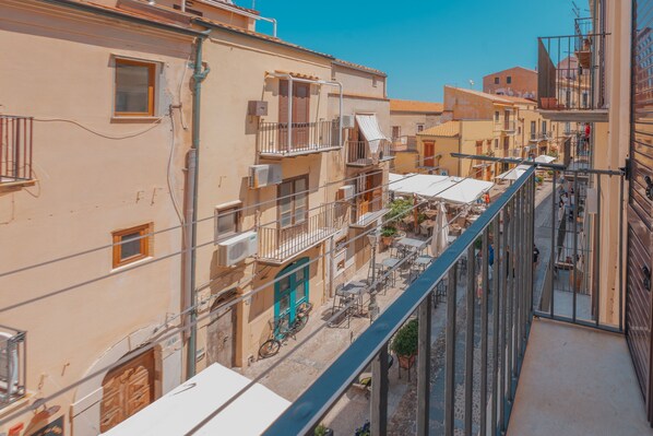 A narrow urban street with buildings featuring balconies and outdoor seating areas. - Casa Silvana a Cefal by Wonderful Italy (Cefalù)