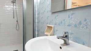 A bathroom with a white sink, a glass shower enclosure, and blue patterned tiles. - Casa Silvana a Cefal by Wonderful Italy (Cefalù)