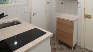 A compact kitchen with a built-in stove, a sink, and a wooden cabinet. - Casa Silvana a Cefal by Wonderful Italy (Cefalù)