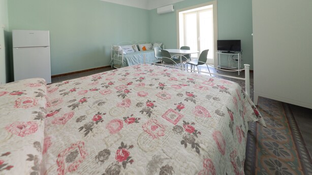 A bedroom with a bed, a desk, a chair, a television, and a refrigerator. - Casa Silvana a Cefal by Wonderful Italy (Cefalù)