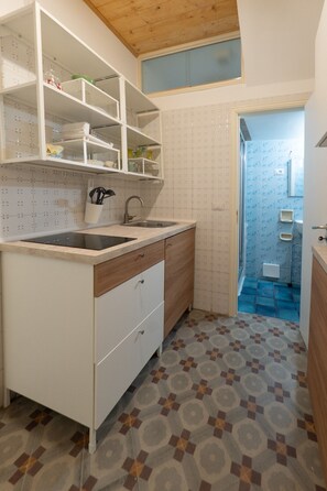 A compact kitchen with white cabinetry, a built-in sink, and patterned floor tiles. - Casa Silvana a Cefal by Wonderful Italy (Cefalù)