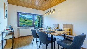Un espace repas comprenant une table en bois, des chaises à revêtement gris et un banc.