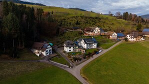 Un village rural avec des maisons, une route sinueuse et une colline en arrière-plan.